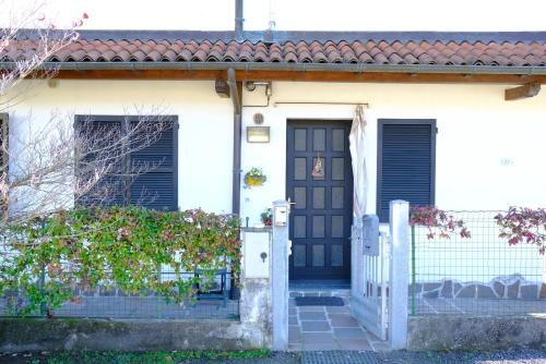 a white house with a black door and a fence at Hotel Il Canneto in Porto Ceresio