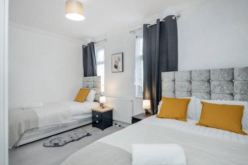 a white bedroom with two beds and yellow pillows at TMS Top Flat! Tilbury! in Tilbury