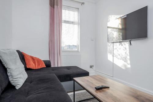 a living room with a black couch and a table at TMS Top Flat! Tilbury! in Tilbury