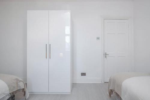 a white bedroom with two beds and a sliding door at TMS Top Flat! Tilbury! in Tilbury