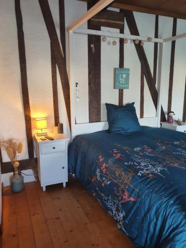 ein Schlafzimmer mit einem Bett mit blauer Decke und einem Nachttisch in der Unterkunft Chambre d'hôtes Le Relais de Belloy in Belloy sur Somme