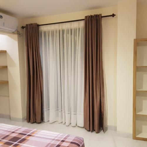 een slaapkamer met een bed en een raam met gordijnen bij Lauwrens Guest House in Makassar