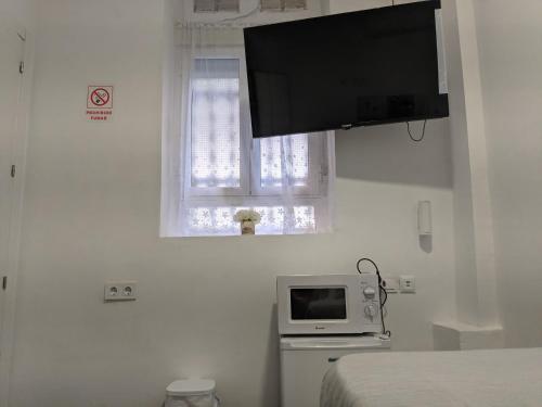 1 dormitorio con TV en la pared junto a una cama en Pension Susita, en Alicante