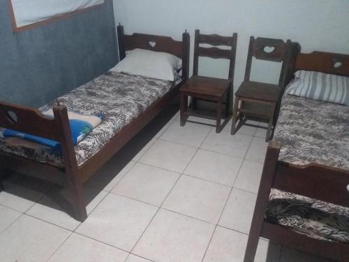 a room with three bunk beds and two chairs at EL CALEUCHE in Rio das Ostras