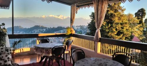 a balcony with tables and chairs and a view of the mountains at Indivar Homestay in Darjeeling