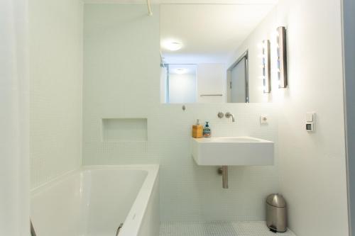 a white bathroom with a sink and a bath tub at FULL HOUSE Premium Apartments Leipzig M14 in Leipzig