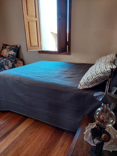 a bed with a blue blanket in a bedroom at Solar dos Tios in São Thomé das Letras