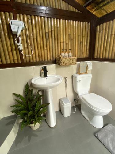 a bathroom with a toilet and a sink at Inigtan Lio Bamboo Cottages in El Nido