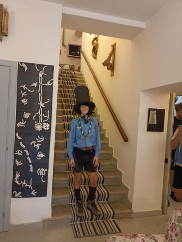 a man in a hat standing on the stairs at Ostello La Miniera in Massa Marittima
