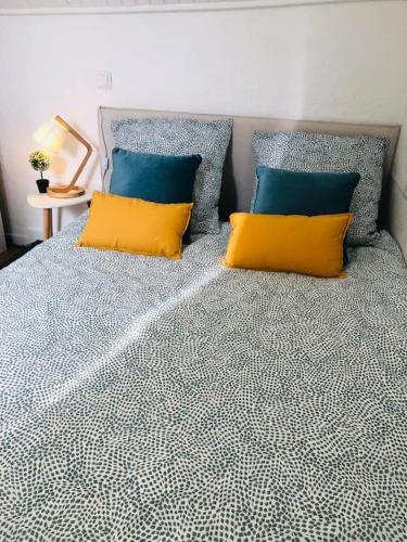 a bed with two blue and yellow pillows on it at Cocooning little house in french Vexin in Us