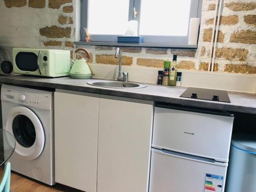een keuken met een wastafel en een wasmachine bij Cocooning little house in french Vexin in Us