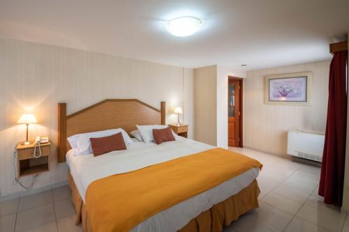 une chambre d'hôtel avec un grand lit et deux lampes dans l'établissement El Prado, à Neuquén