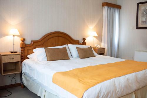 a large bed in a hotel room with two lamps at El Prado in Neuquén