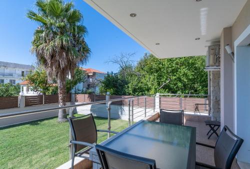 a balcony with a table and chairs and a palm tree at Oniro Luxury Villas in Toroni