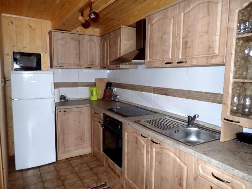 cocina con armarios de madera, fregadero y nevera en Chata Krpáčovo en Horná Lehota
