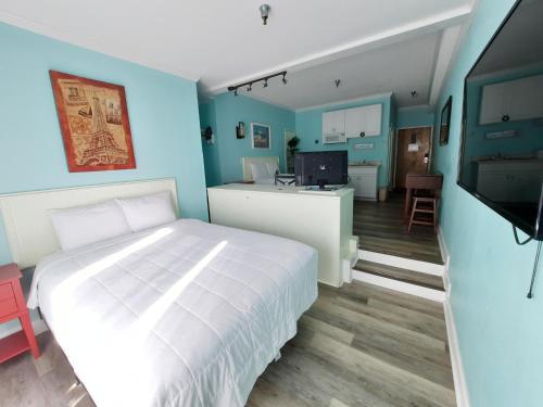 a bedroom with a white bed and a blue wall at Palm Suites in Atlantic Beach