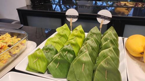 a bunch of green food on a table with tongs at DUM Hotel - Si Phum in Chiang Mai