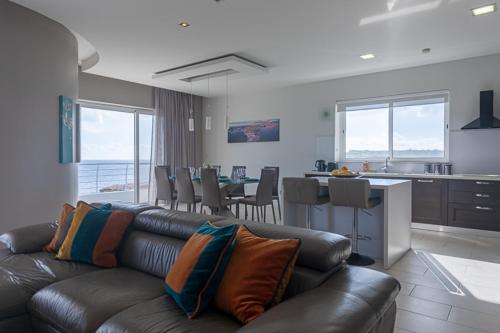 a living room with a leather couch and a kitchen at Waters-Edge Complex in Marsaskala
