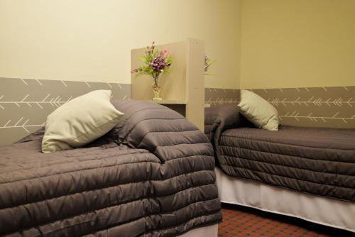Habitación con 2 camas, sofá y flores en HOSTEL KUYUK en Mendoza