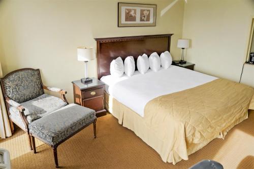 a bedroom with a large bed and a chair at Economy Hotel Plus Wichita in Wichita