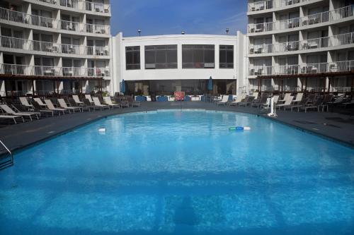 une grande piscine avec des chaises et un bâtiment dans l'établissement Quality Inn & Suites Oceanfront, à Virginia Beach