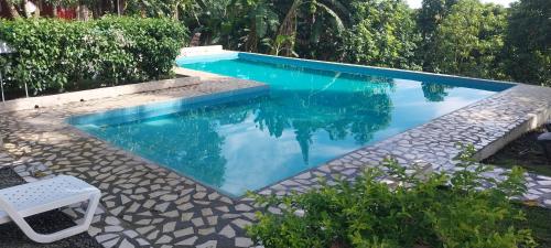 a swimming pool with a white chair next to it at Hotel Cabañas Casita La Ermita in San Carlos