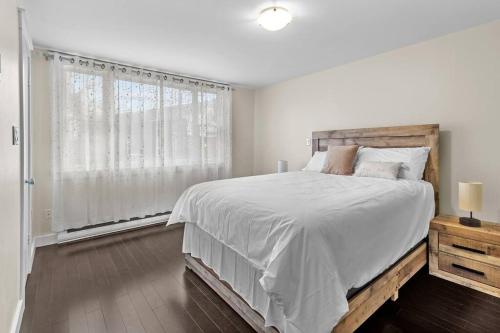 a white bedroom with a large bed and a window at Beautiful & Cozy DT Home With PingPong Table in St. John's