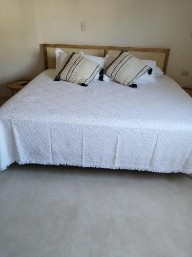 a white bed with two pillows on top of it at Casa Bizu in Bacalar
