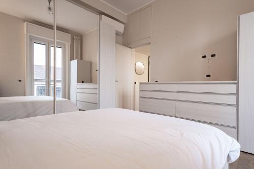 a white bedroom with two beds and a window at Montello Livings, Exclusive terrace and skyline view in Milan