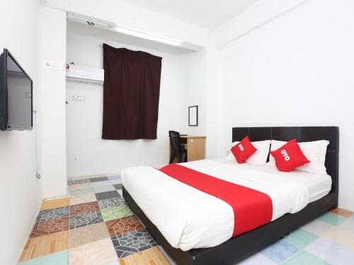 een slaapkamer met een bed met rode kussens en een televisie bij Kb Rest Inn-Deluxe Queen in Kota Bharu