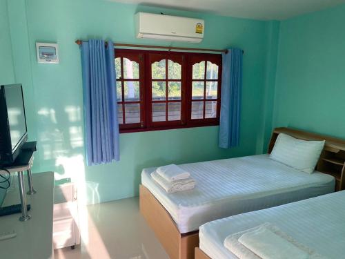 a room with two beds and a television and a window at The An Ant บ้านพัก&โฮมสเตย์ in Sam Roi Yot