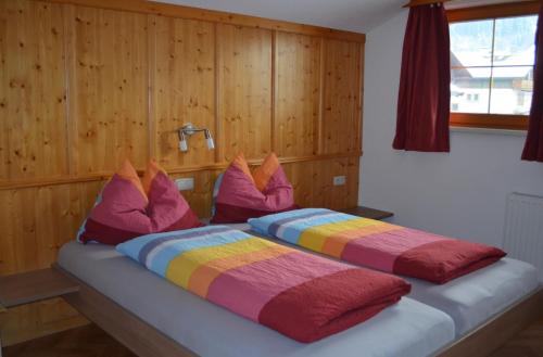 ein großes Bett mit bunten Kissen darüber in der Unterkunft Kienberghof in Reith im Alpbachtal