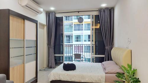Un dormitorio con una cama y una ventana con un gato. en Greenfield Regency Comfort Suite - Wifi 4pax Paradigm & Sutera, en Johor Bahru
