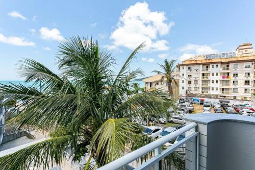 uma varanda com uma palmeira e um parque de estacionamento em Predio com apartamentos completos, com piscina e a passos da praia - Agua Marinha em Florianópolis