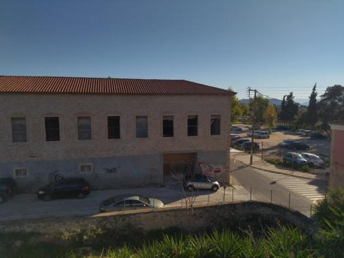 a building with cars parked in a parking lot at Captain's Rooms in Aegina Town