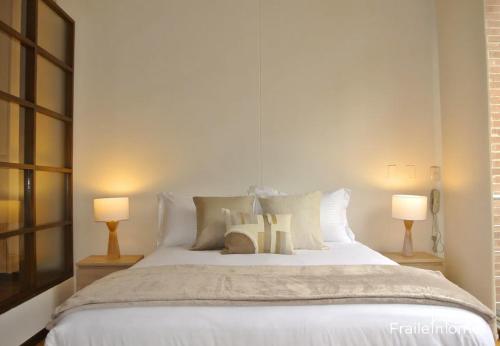 1 dormitorio con 1 cama blanca grande y 2 lámparas en FH - Stylish loft in Chico Norte - Bogota en Bogotá