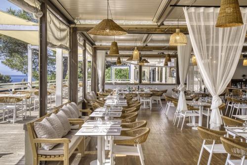 un restaurant avec des tables et des chaises blanches dans l'établissement Belambra Clubs Presqu'île De Giens - les Criques, à Hyères