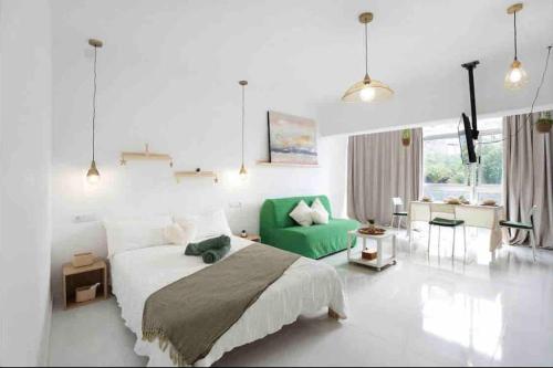 ein Schlafzimmer mit einem großen Bett und einem grünen Sofa in der Unterkunft Paradise Studio Belair WiFi, piscina, parking in Puerto de la Cruz