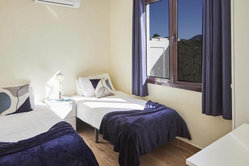 two beds in a room with a window at Villa Cantium - LH101 By Villas Now Ltd in Playa Blanca
