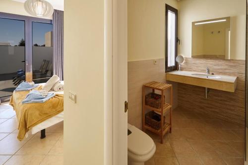 a bathroom with a sink and a toilet and a mirror at Villa Cantium - LH101 By Villas Now Ltd in Playa Blanca
