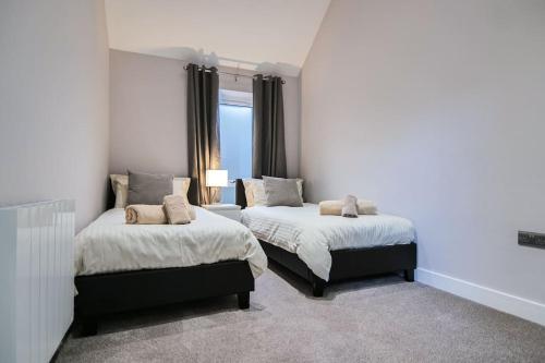 a bedroom with two beds and a window at Hoxne Cottages - Rose Cottage with private hot tub in York