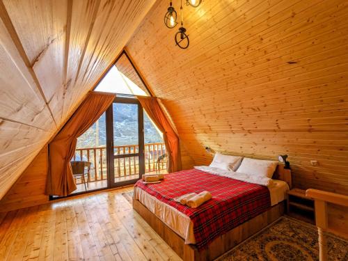 a bed in a wooden room with a large window at Cottage Caucasus in Kazbegi