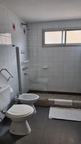 a white bathroom with a toilet and a sink at Hotel Agustin Garcia in Tigre