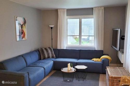 un soggiorno con divano blu e TV di Vakantiehuis SARAH- vlakbij meer- van S&G Holiday a Nykroppa
