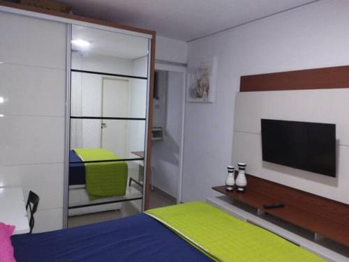 um quarto com uma cama e uma televisão na parede em Apartamento bairro Praia do Canto na Reta da Penha em Vitória
