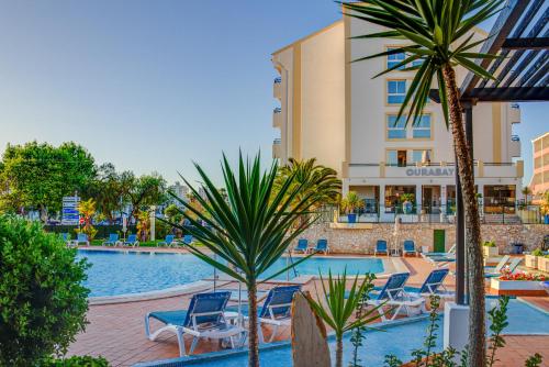 una piscina con sillas y un hotel en Ourabay Hotel Apartamento - Art & Holidays en Albufeira