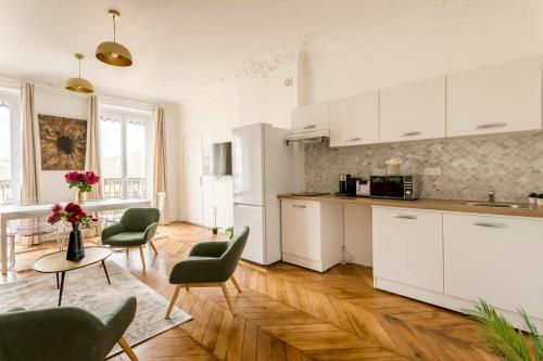 una cucina con armadi bianchi e sedie verdi di Cosy 5 Bedrooms and 2 Bathrooms - Le Marais a Parigi