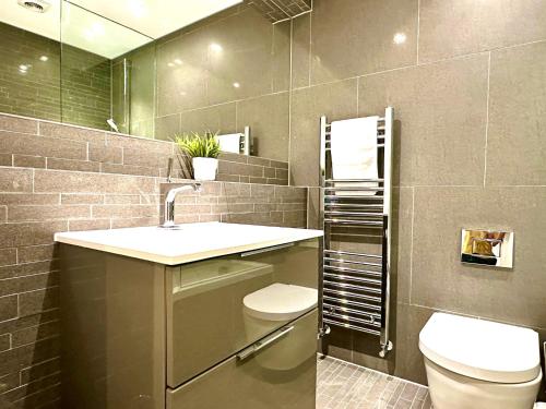 a bathroom with a sink and a toilet and a mirror at Beautiful New 2 Bedroom Apartment - Next to the Beach - Great Location - FREE Parking - Fast WiFi - Smart TV - sleeps up to 4! Close to Purbeck, Corfe Castle, Sandbanks, Poole & Bournemouth in Swanage