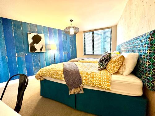 a bedroom with a bed and a blue wall at Beautiful New 2 Bedroom Apartment - Next to the Beach - Great Location - FREE Parking - Fast WiFi - Smart TV - sleeps up to 4! Close to Purbeck, Corfe Castle, Sandbanks, Poole & Bournemouth in Swanage