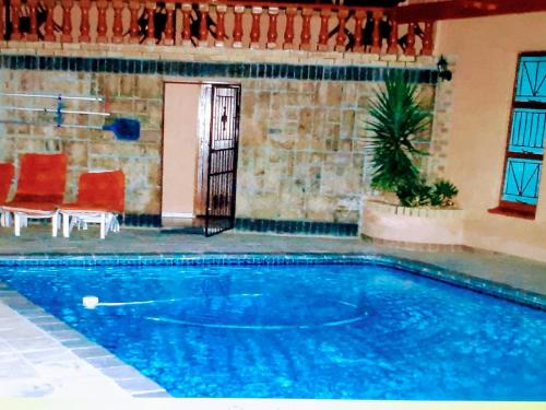 a large swimming pool with red chairs and a door at Valley View Guest House in Mogwase
